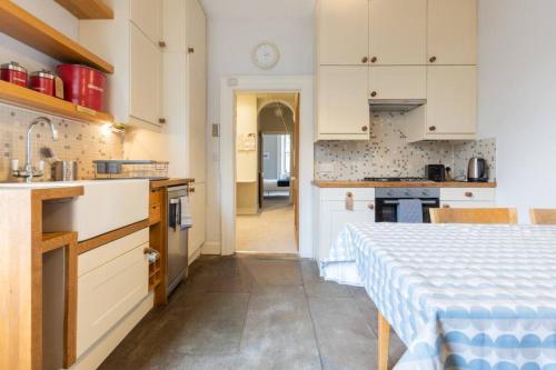a kitchen with white cabinets and a table at Beautiful 1 Bedroom Flat in Vibrant Stockbridge in Edinburgh