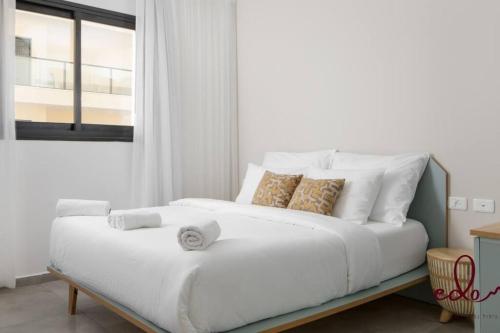 ein weißes Bett in einem Zimmer mit Fenster in der Unterkunft דירת משפחתית 2 חדרי שינה במיקום מרכזי - By Edom in Eilat