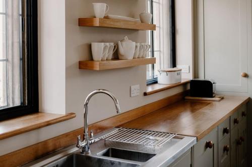 a kitchen with a sink and wooden shelves at The Courtyard at Manor Estate near Stonehenge in Salisbury