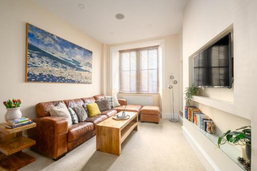 a living room with a brown leather couch and a table at Stylish & Central 2BR Stockbridge Gem in Edinburgh