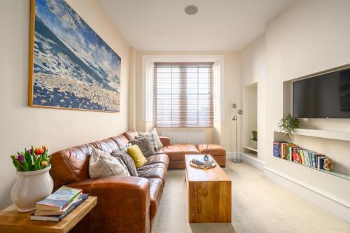 a living room with a brown leather couch and a table at Stylish & Central 2BR Stockbridge Gem in Edinburgh