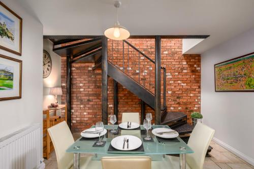 a dining room with a table and chairs and a brick wall at Stylish & Central 2BR Stockbridge Gem in Edinburgh