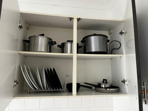 a shelf with pots and pans and utensils in a kitchen at Cosy one-bedroom furnished flat! in Seven Kings