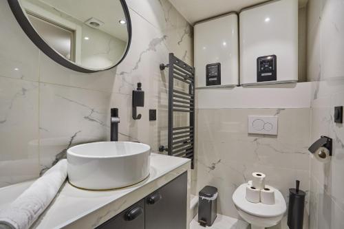 une salle de bain blanche avec un lavabo et un miroir dans l'établissement Apartment St Honore by Studio prestige, à Paris