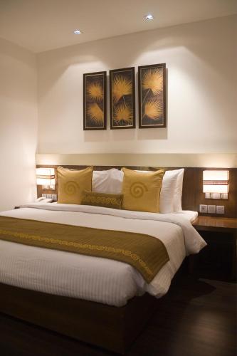 a bedroom with a large bed with yellow pillows at Shervani Nehru Place in New Delhi