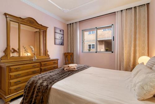 een slaapkamer met een bed met een ladekast en een spiegel bij Costamar Arinaga in Arinaga