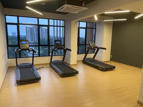 ein Fitnessraum mit vier Laufbändern in einem Zimmer mit Fenstern in der Unterkunft Theda Antara Putrajaya with Wifi and Netflix in Putrajaya