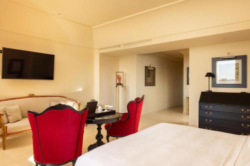 a bedroom with a bed and a desk and red chairs at Alvino Relais Mulino Contemporaneo in Matera