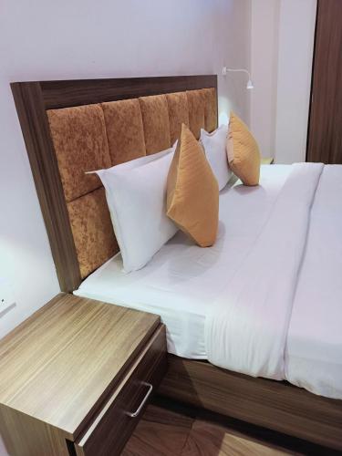 un letto con lenzuola e cuscini bianchi e testiera in legno di CT ROOMS JAMAL ROAD by CLOVETREE a Patna