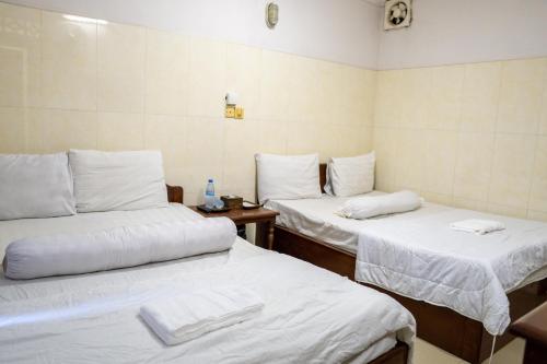 um quarto com duas camas com lençóis brancos em Empire House, Phnom Penh em Phnom Penh