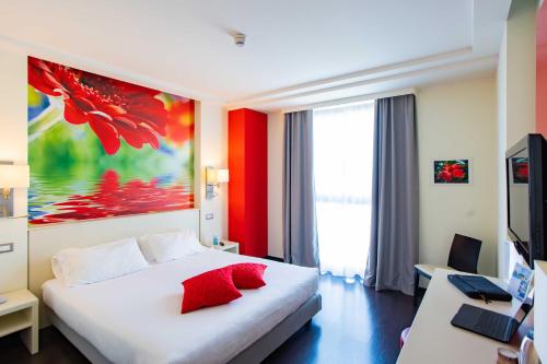 a bedroom with a white bed with red pillows at AN Hotel Milano Melegnano in Carpiano