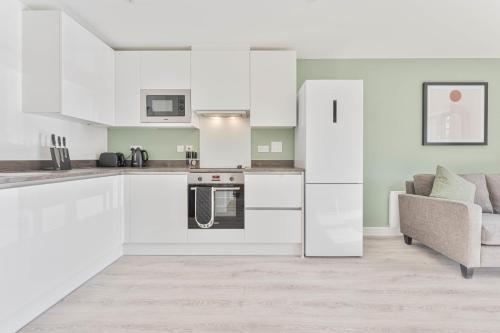 a kitchen with white cabinets and a couch at StayZeni, Hardwick House Derby Lovely 1 Bed Flat in Derby