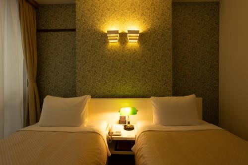 a hotel room with two beds and a table with a lamp at Kikunoya in Miyajima