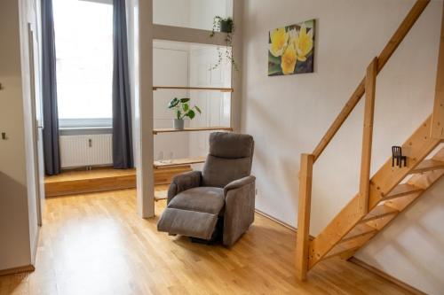 een woonkamer met een stoel en een trap bij Gemütliches Studio mit Hochbett im Herzen von Graz in Graz