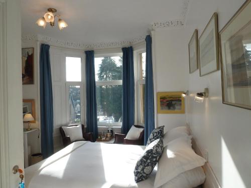 a bedroom with a large white bed with blue curtains at Failte Bed & Breakfast in Oban