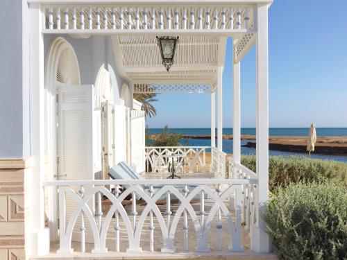 a white porch with a table and chairs on the beach at La Maison Bleue El Gouna in Hurghada