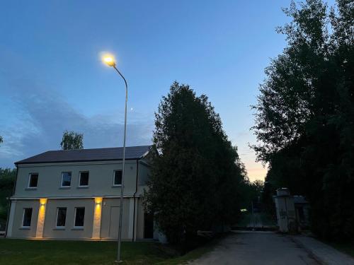 a white house with a street light in front of it at Art&Comfort Country in Kaunas