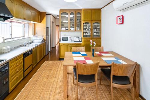 a kitchen with a wooden table and chairs at ゲストハウス　luluha in Awatabe