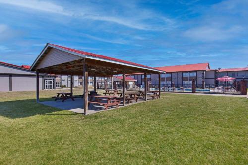 a picnic shelter with tables and umbrellas in the grass at Ramada by Wyndham Bowling Green in Bowling Green