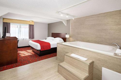 a hotel room with a bed and a bath tub at Ramada by Wyndham Bowling Green in Bowling Green