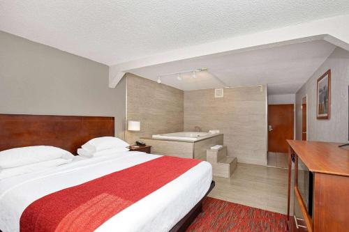 a hotel room with a bed and a bath tub at Ramada by Wyndham Bowling Green in Bowling Green