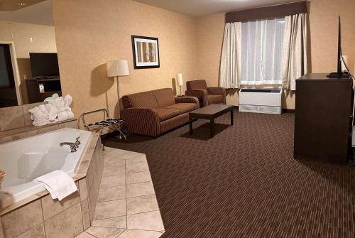 Habitación de hotel con bañera y sala de estar. en Ramada by Wyndham Estevan, en Estevan