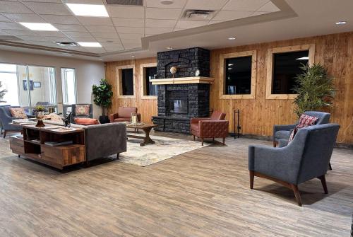 a lobby with a fireplace and chairs and a table at Ramada by Wyndham Estevan in Estevan