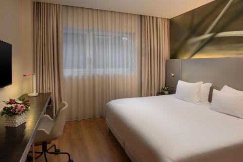 a hotel room with a large bed and a desk at NH Orio Al Serio in Orio al Serio