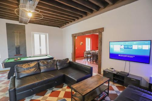 ein Wohnzimmer mit einem Ledersofa und einem Flachbild-TV in der Unterkunft Crazy Villa Champs Corons 61 - Interior heated pool - 2h from Paris - 30p in Les Menus
