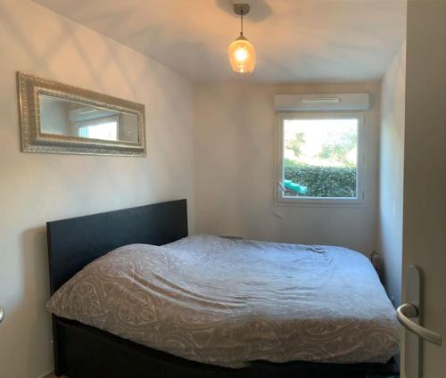 une chambre avec un lit avec un miroir et une fenêtre dans l'établissement Appartement T3 rez de jardin, résidence piscine, à Fréjus