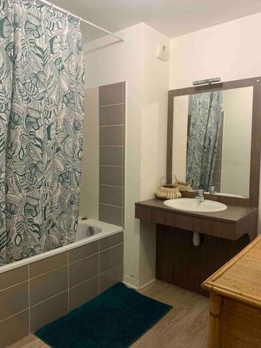 une salle de bain avec un lavabo et un rideau de douche dans l'établissement Appartement T3 rez de jardin, résidence piscine, à Fréjus