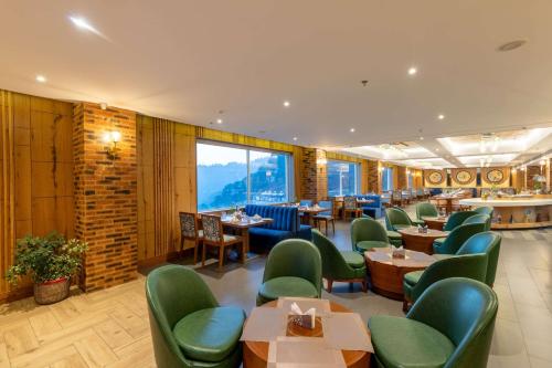 a restaurant with green chairs and tables and windows at Ramada by Wyndham Kasauli in Kasauli
