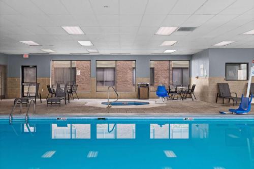 a pool with chairs and tables in a room at AmericInn by Wyndham Casper Event Center Area in Casper