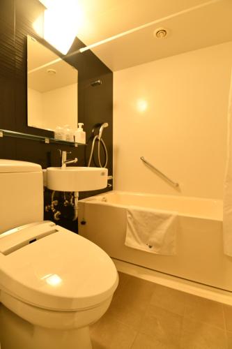 a bathroom with a toilet and a sink and a tub at Kikunoya in Miyajima