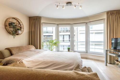 a bedroom with a bed and a large window at Top studio Knokke bij zeedijk! in Knokke-Heist
