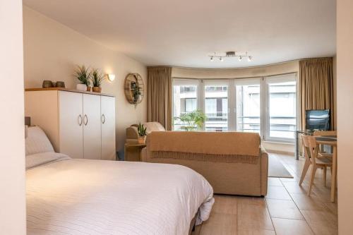a bedroom with a bed and a table and a kitchen at Top studio Knokke bij zeedijk! in Knokke-Heist