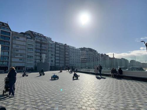 a group of people sitting on a sidewalk in a city at Top studio Knokke bij zeedijk! in Knokke-Heist