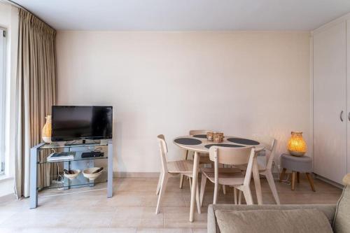 a living room with a table and a tv at Top studio Knokke bij zeedijk! in Knokke-Heist