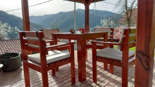 a wooden table and chairs on a patio with a view at Ljubov kutak in Mokra Gora