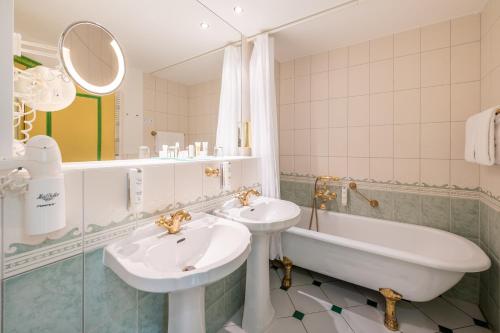 y baño con 2 lavabos, bañera y bañera. en Rugard Thermal Strandhotel en Binz