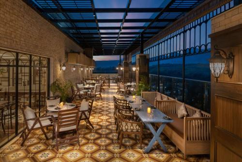 a restaurant with tables and chairs on a balcony at Hyatt Centric Rajpur Road Dehradun in Dehradun