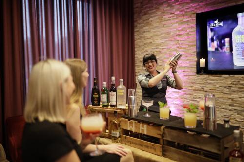 a man standing at a bar holding a bottle of wine at Holiday Inn Lübeck by IHG in Lübeck