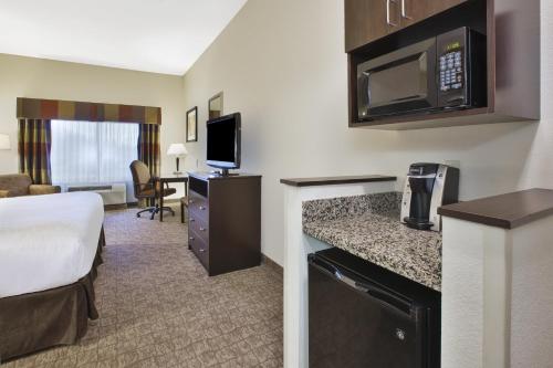 a hotel room with a king sized bed and a kitchen at Holiday Inn Express and Suites Wheeling by IHG in Triadelphia