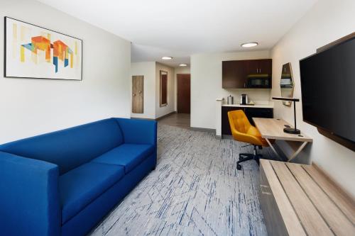 a living room with a blue couch and a desk at Holiday Inn Express and Suites Wheeling by IHG in Triadelphia