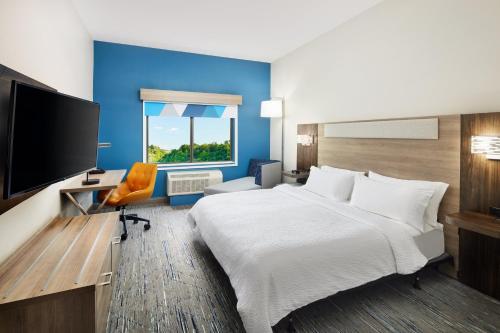 a hotel room with a bed and a flat screen tv at Holiday Inn Express and Suites Wheeling by IHG in Triadelphia