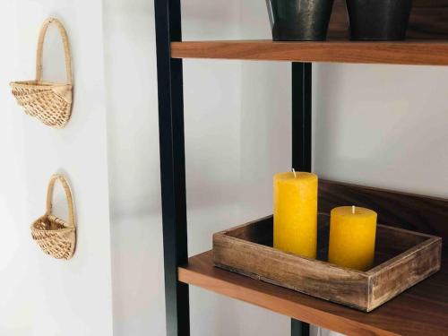two candles in a wooden tray on a shelf at Appartement duplex cosy in Cormicy