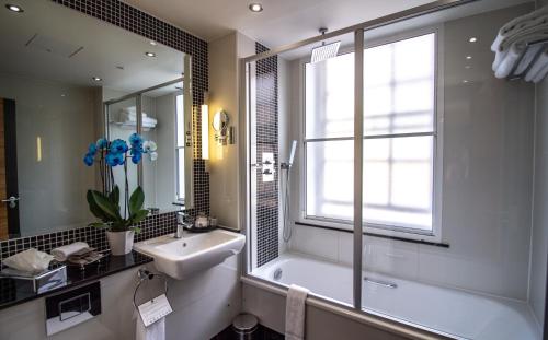 a bathroom with a tub and a sink and a window at Rochester Hotel by Blue Orchid in London