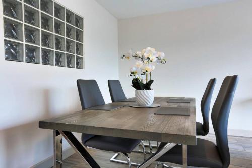 una mesa de comedor con un jarrón de flores. en Modern 3 bedroom apartment with city river views en Dublín