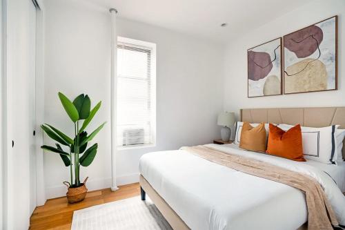 um quarto com uma cama com almofadas laranja e uma planta em 403-4C New 2br 2baths prime ues em Nova York
