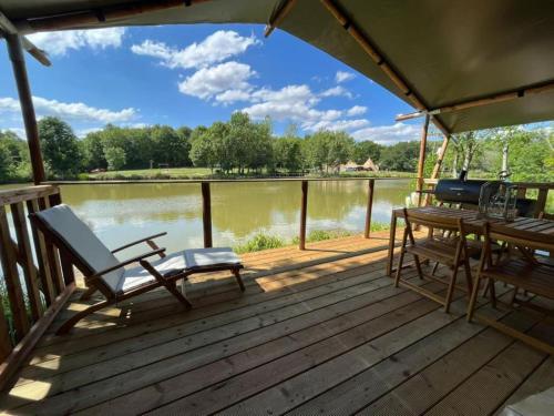 a deck with a table and chairs and a view of a lake at Kingfisher Safari Tent in Droitwich